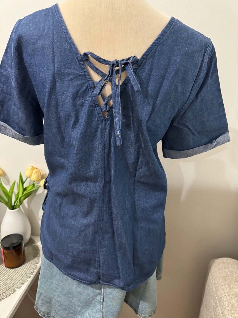 Kashieca Denim Blouse Size Large (Category: Blouses) located in Quezon. Submitted by ja8720 (Listing ID 1471048274, Image 2). Description: - Brand: Kashieca - Size: Large - Material: Soft, comfortable denim - Design: Short sleeves with folded cuffs, side tie detail on the left hip - Back Detail: Trendy lace-up strap design with ribbons - Condition: Good overall condition, ideal for casual wear.