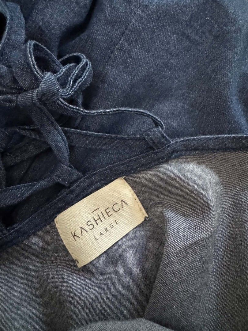 Kashieca Denim Blouse Size Large (Category: Blouses) located in Quezon. Submitted by ja8720 (Listing ID 1471048274, Image 3). Description: - Brand: Kashieca - Size: Large - Material: Soft, comfortable denim - Design: Short sleeves with folded cuffs, side tie detail on the left hip - Back Detail: Trendy lace-up strap design with ribbons - Condition: Good overall condition, ideal for casual wear.