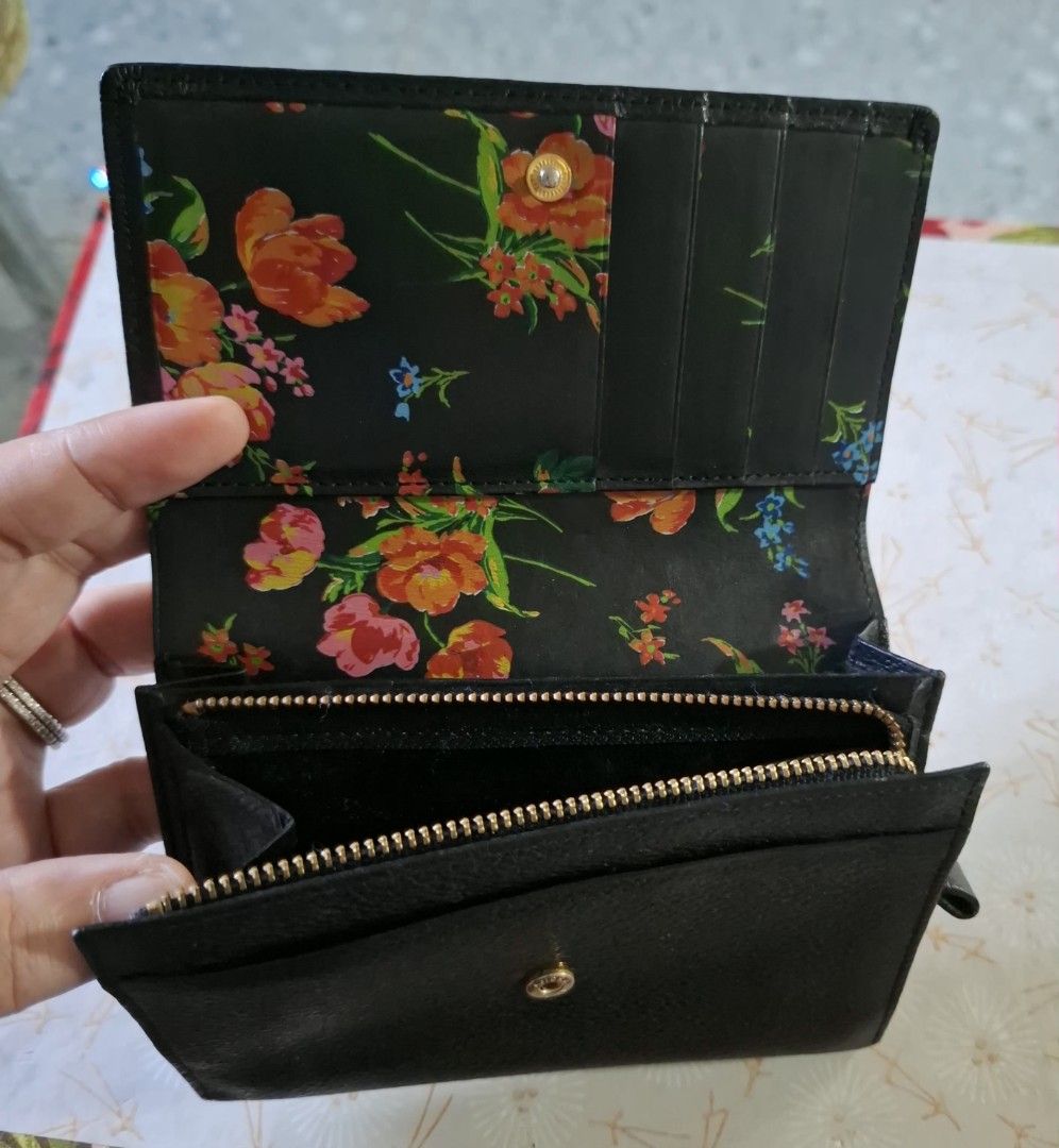 Kenzo Black Leather Wallet with Floral Interior (Category: Wallets & Card holders) located in Don Carlos. Submitted by PphiXi_Finds (Listing ID 1470942052, Image 3). Description: - Brand: Kenzo - Material: Black textured leather with gold-tone logo lettering - Interior: Vibrant colorful floral print lining - Features: Card slots, cash compartments, and a secure zippered coin pocket - Closure: Gold snap button - Size: Compact and handy for everyda