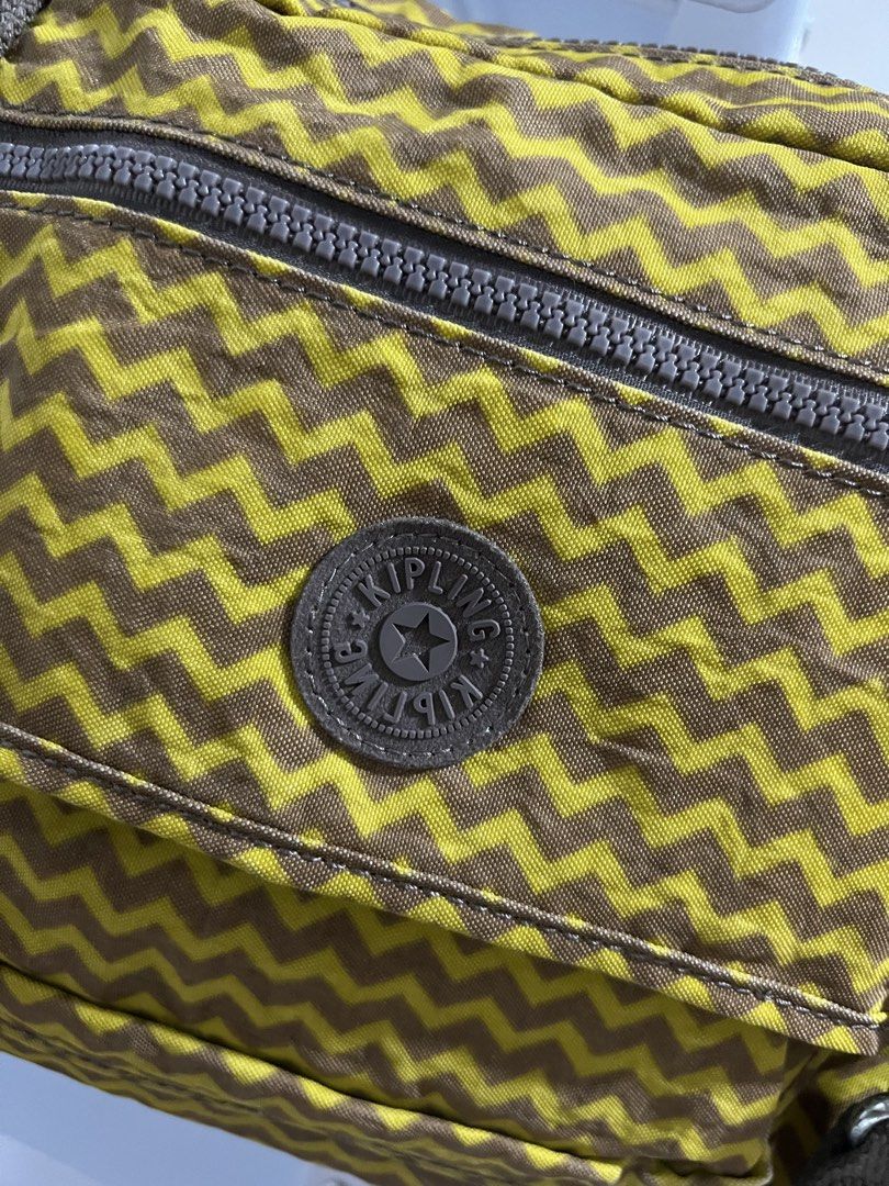 Kipling Brown Yellow Chevron Pattern Crossbody Bag with Monkey Keychain (Category: Cross-body Bags) located in Muntinlupa City. Submitted by armendaber03743 (Listing ID 1471092103, Image 2). Description: Kipling crossbody bag in a yellow and brown chevron pattern. Brown canvas adjustable shoulder strap and matching vertical strap details on the front flap. Includes a zippered front pocket and the classic round Kipling logo patch. Fuzzy brown monk