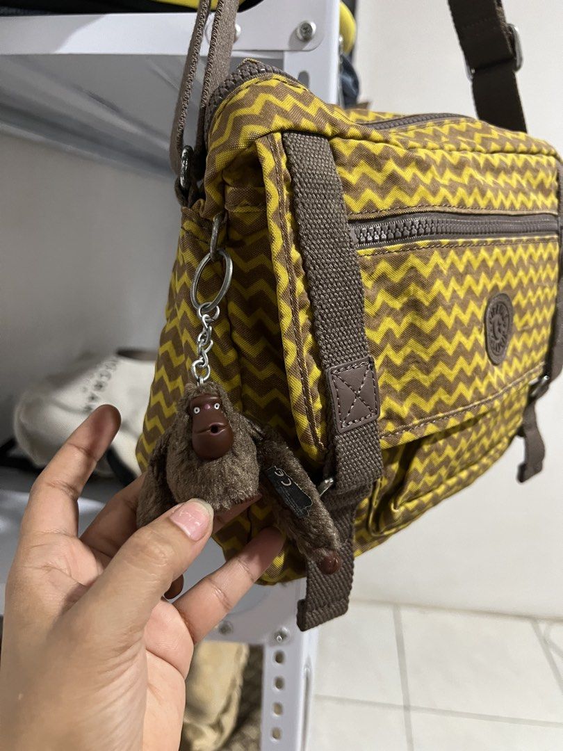 Kipling Brown Yellow Chevron Pattern Crossbody Bag with Monkey Keychain (Category: Cross-body Bags) located in Muntinlupa City. Submitted by armendaber03743 (Listing ID 1471092103, Image 3). Description: Kipling crossbody bag in a yellow and brown chevron pattern. Brown canvas adjustable shoulder strap and matching vertical strap details on the front flap. Includes a zippered front pocket and the classic round Kipling logo patch. Fuzzy brown monk