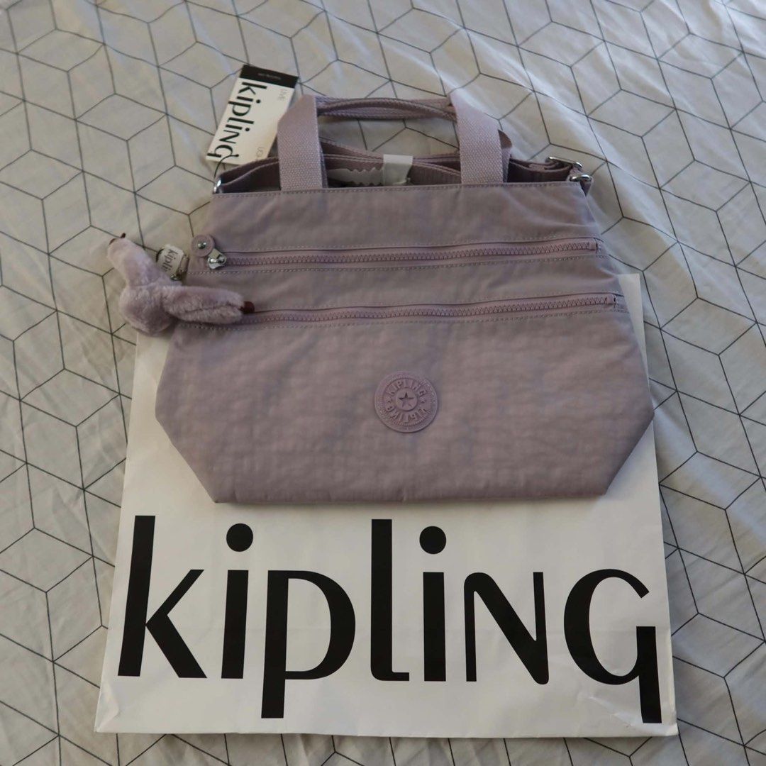 Kipling Miah Serene Lavender Tote Bag (Category: Tote Bags) located in Manila. Submitted by mixi_lexi (Listing ID 1471048306, Image 2). Description: - Brand: Kipling Miah Tote Bag - Color: Serene Lavender (Style Code: KI9462) - Material: Durable signature crinkle nylon - Features: Multiple zippered front compartments & top carry handles - Includes: Iconic furry purple monkey keychain charm - Condition: Brand new in original plastic packaging with