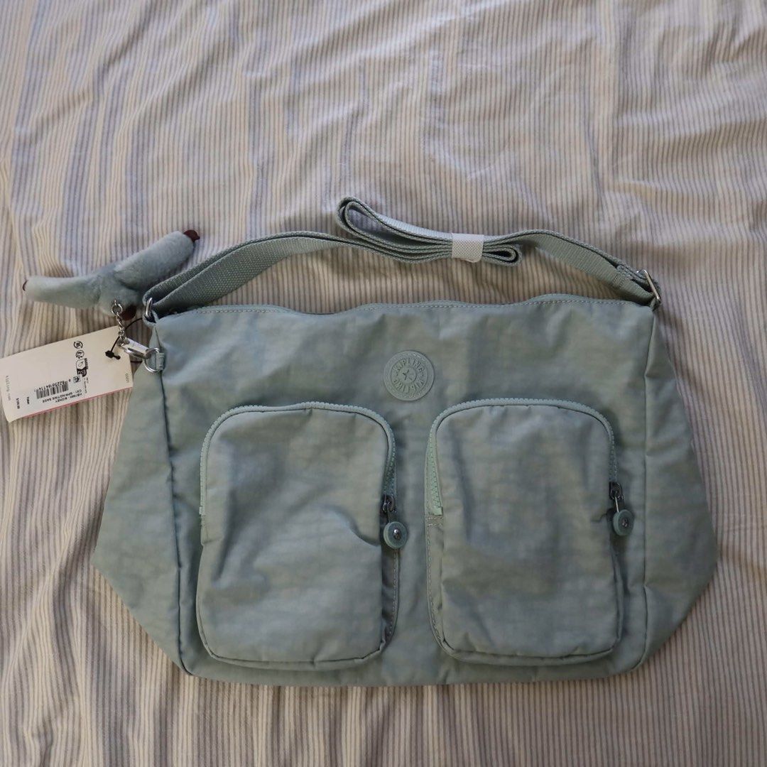 Kipling Sidney Handbag Springtime Sage (Category: Luxury Bags & Wallets) located in Manila. Submitted by mixi_lexi (Listing ID 1471048330, Image 2). Description: - Brand: Kipling - Style: Sidney Shoulder Bag (Model HB7685 CX1) - Colorway: Springtime Sage - Dimensions: 13.5" x 10" x 6" - Includes matching Arianna furry monkey keychain - Features two front exterior zippered pockets - Condition: Brand new with original tags attached (Retail price: $