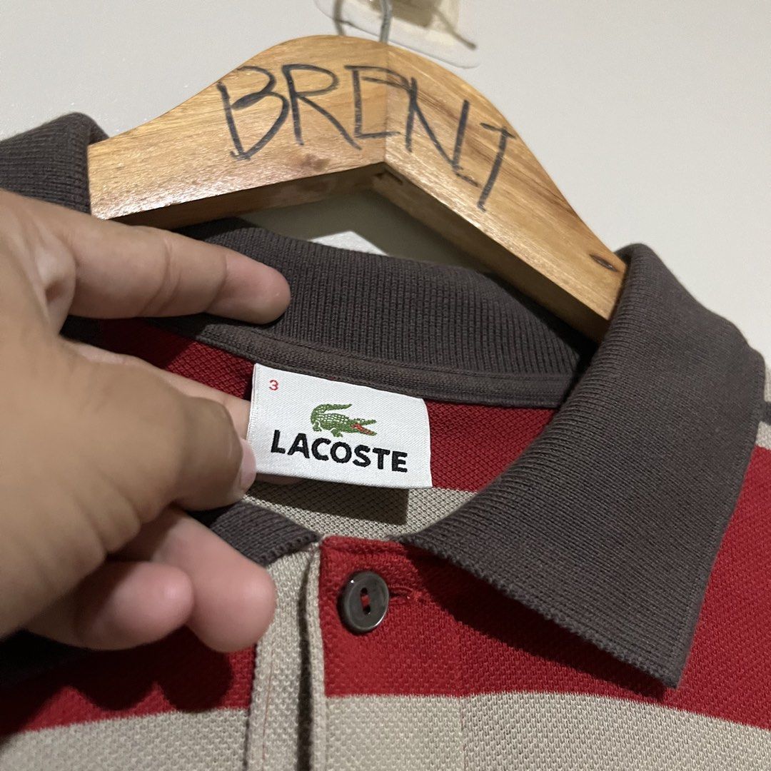 Lacoste Devanlay Long Sleeve Striped Polo Shirt (Category: Tshirts & Polo Shirts ) located in Argao. Submitted by secondcyclecollection (Listing ID 1471068963, Image 3). Description: - Brand: Lacoste - Size : Medium To Large - Style: Long sleeve polo shirt with horizontal stripes (red, beige, dark brown) - Details: Dark brown collar, sleeve cuffs, and three-button placket with dark buttons - Branding: Iconic embroidered crocodile logo on the left