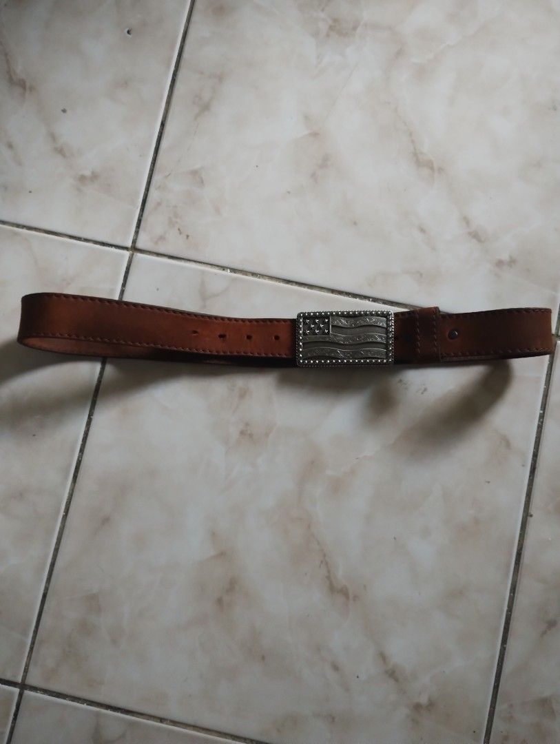 Leather Belt With American Flag Buckle (Category: Belts) located in Imus. Submitted by darylg88358770 (Listing ID 1471023278, Image 2). Description: - Style: Classic Western style - Strap: Genuine brown leather with sturdy edge stitching - Buckle: Silver-tone metal plate featuring an embossed American flag, stars, and floral scroll patterns - Closure: Standard pin buckle on the back - the items trifted fresh from bale size 34 .