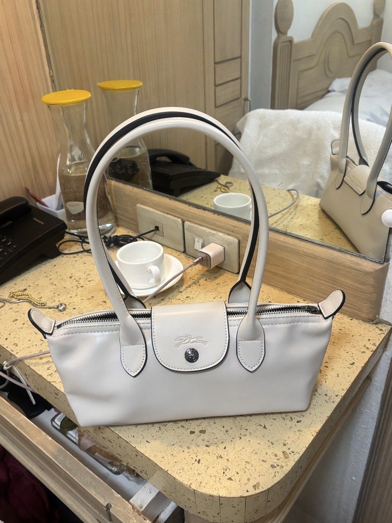 Longchamp Le Pliage Extra Small Handbag Off White (Category: Luxury Bags & Wallets) located in Paranaque City. Submitted by ciangggg (Listing ID 1470936870, Image 3). Description: - Features a classic foldover flap with signature horse rider logo snap button - Secure zip closure with structured top handles - Smooth leather finish complemented by stylish contrast piping - Compact and lightweight design, ideal for shoulder or hand carry - Clean, mi