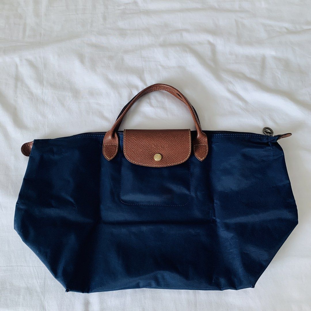 Longchamp Le Pliage Navy Blue Tote Bag (Category: Luxury Bags & Wallets) located in Makati City. Submitted by aliahs_personal_item (Listing ID 1470976809, Image 3). Description: - Brand: Longchamp Le Pliage - Color: Dark Navy Blue with Brown Leather Handles and Flap - Hardware: Gold-tone snap button with zip top closure - Material: Durable, lightweight, and foldable nylon - Condition: Clean interior, crisp exterior fabric, and well-maintained - F