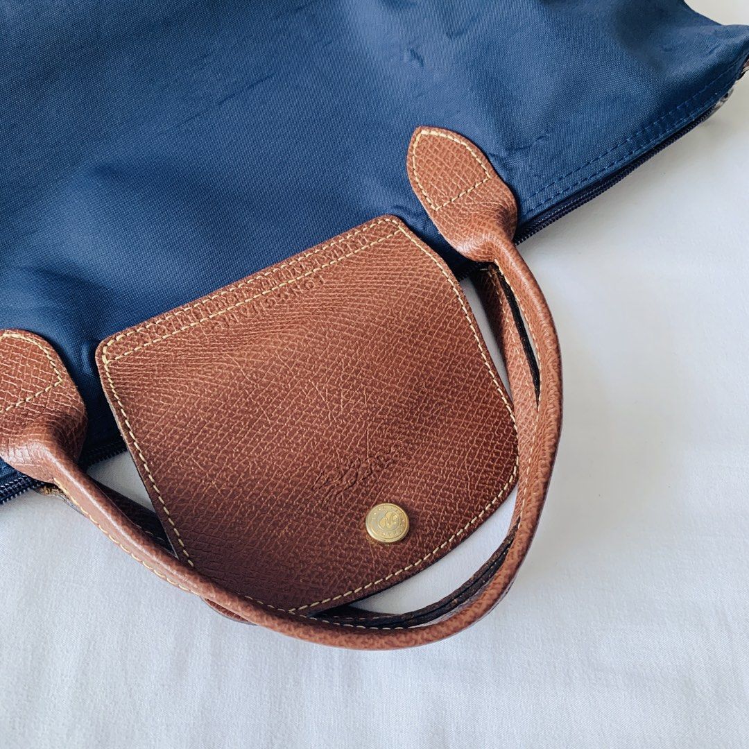 Longchamp Le Pliage Navy Blue Tote Bag (Category: Luxury Bags & Wallets) located in Makati City. Submitted by aliahs_personal_item (Listing ID 1470976809, Image 2). Description: - Brand: Longchamp Le Pliage - Color: Dark Navy Blue with Brown Leather Handles and Flap - Hardware: Gold-tone snap button with zip top closure - Material: Durable, lightweight, and foldable nylon - Condition: Clean interior, crisp exterior fabric, and well-maintained - F