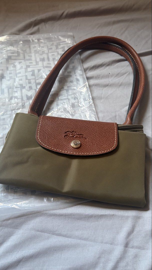 Longchamp Le Pliage Olive Green Tote Bag (Category: Luxury Bags & Wallets) located in Manila. Submitted by pengudk (Listing ID 1470978204, Image 1). Description: - Color: Olive green with brown leather handles and flap - Hardware: Gold-tone zipper pull featuring the iconic jockey logo - Material: Durable, clean nylon body with traditional Russian leather trim - Design: Folds down flat for easy storage and snaps shut securely - Perfect For: Daily 