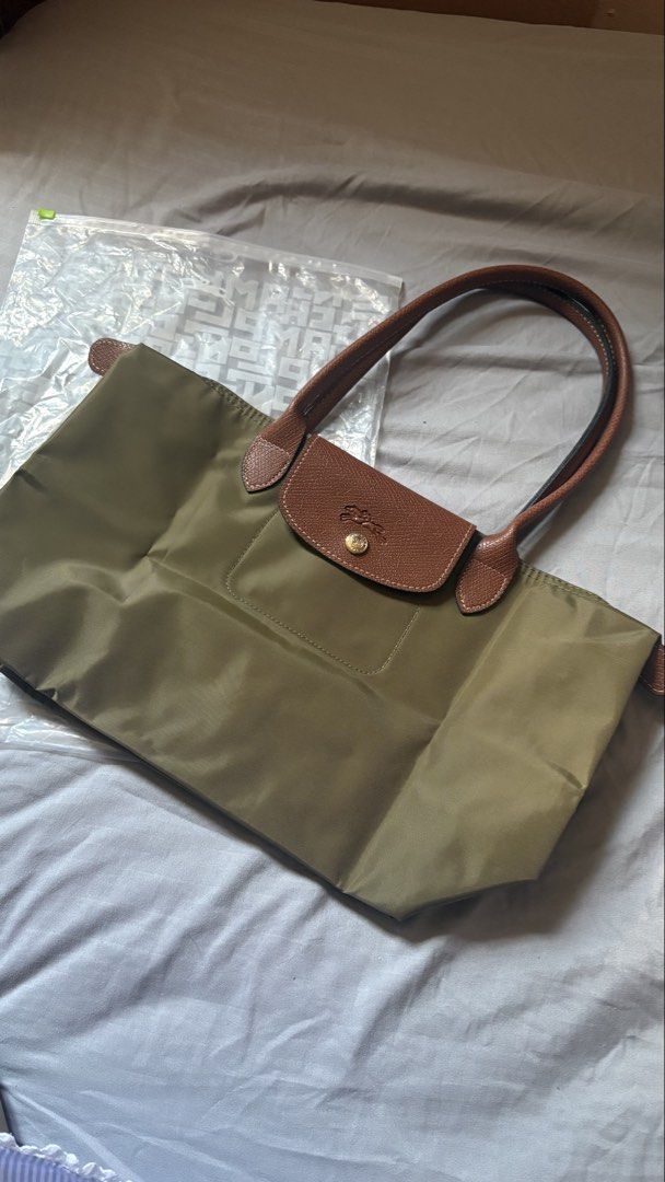 Longchamp Le Pliage Olive Green Tote Bag (Category: Luxury Bags & Wallets) located in Manila. Submitted by pengudk (Listing ID 1470978204, Image 2). Description: - Color: Olive green with brown leather handles and flap - Hardware: Gold-tone zipper pull featuring the iconic jockey logo - Material: Durable, clean nylon body with traditional Russian leather trim - Design: Folds down flat for easy storage and snaps shut securely - Perfect For: Daily 