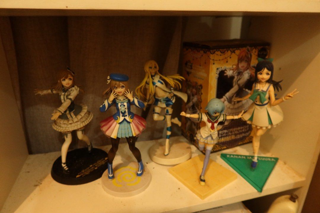 Love Live! Anime Figure Lot (Category: Figurines & Statues) located in Arayat. Submitted by sunnydienna (Listing ID 1471060289, Image 1). Description: Bundle of multiple Love Live! character figures. Includes Kanan Matsuura with her green triangular base. Various poses and outfits shown across the shelf display. Dust present on some surfaces from shelf storage. Great addition for any anime collector looking to expand their display setup. with 2 f