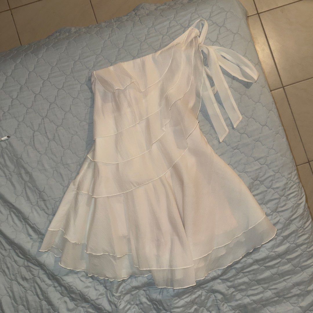 Lovito One-Shoulder Ruffle Dress (Category: Dresses) located in Manila. Submitted by shopmakii (Listing ID 1471093760, Image 2). Description: - Brand: Lovito - Style: One-shoulder asymmetric dress with layered ruffles and tie-shoulder strap - Color: Solid White - Size: XS (EU 32, US 2) - Features: Flowy tiered skirt hemline, lightweight fabric, and inner lining - Perfect for: Casual outings, dates, and summer events.