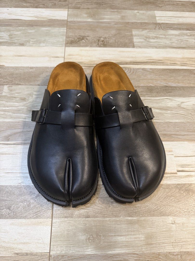 Maison Margiela Tabi Clog Black Leather Slides (Category: Slippers & Slides) located in Manila. Submitted by safeowl.b6dbb0 (Listing ID 1471023680, Image 1). Description: - Brand: Maison Margiela - Style: Black Leather Tabi Clogs - Features: Iconic split-toe design, adjustable side buckle straps, tan suede footbed, rugged rubber lug soles, and signature white heel stitch - Condition/Care: Slip-on style, extremely comfortable and sturdy, carefully