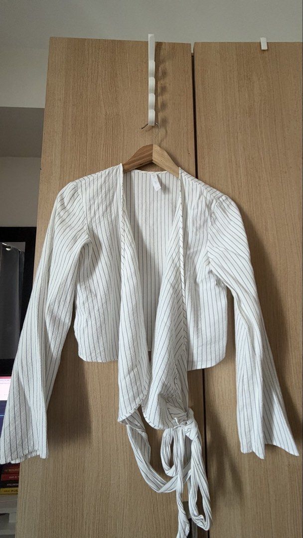 Mango Striped Wrap Blouse (Category: Blouses) located in Mandaluyong City. Submitted by andreyamari_ (Listing ID 1470983043, Image 1). Description: - Brand: Mango - Color: White with thin black vertical stripes - Style: Wrap top with self-tie waist and cropped length - Sleeves: Long flared sleeves - Size: S - Condition: Excellent pre-loved condition - Perfect for casual outings or office chic looks!.