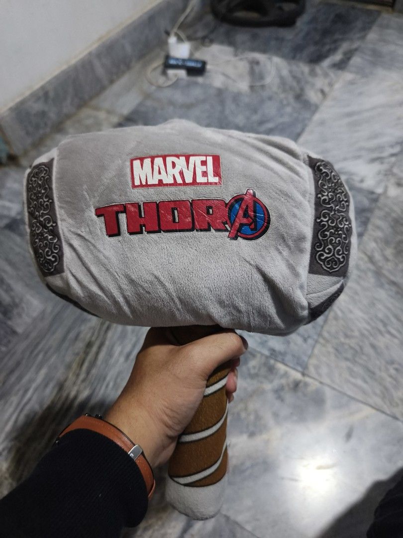 Marvel Avengers Thor Hammer Plush Toy (Category: Plushies & Soft Toys) located in Iligan City. Submitted by sneakymagician (Listing ID 1471022551, Image 3). Description: Soft plush Thor hammer from Marvel Avengers. Grey head with printed Marvel and Thor graphics, brown handle with white stripes. Official Marvel tag attached at the base. Great collectible item or pillow for fans..