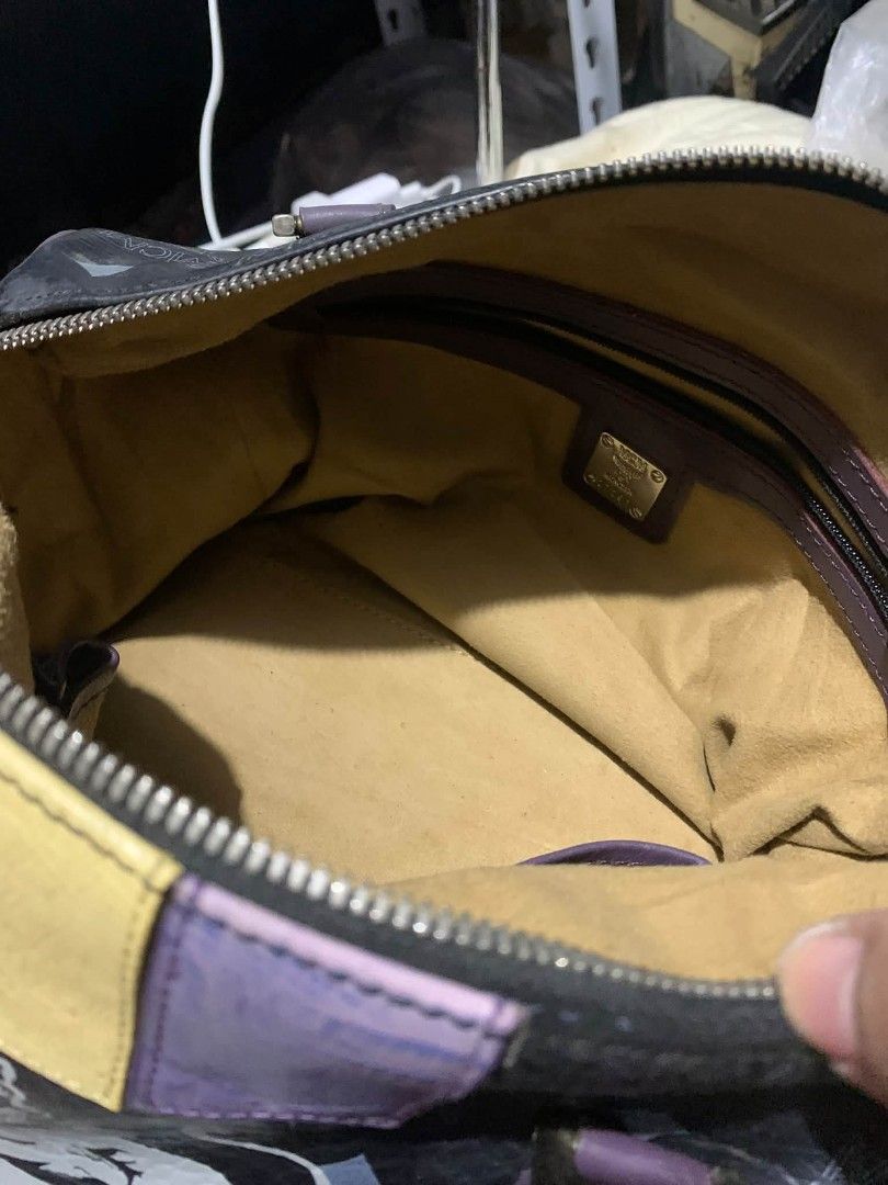 MCM Black Monogram Lion Boston Bag (Category: Luxury Bags & Wallets) located in Daraga. Submitted by thethriftcity2024 (Listing ID 1470981221, Image 3). Description: - Black MCM Boston bag with classic monogram print - Features a bold, large white lion graphic on the side - Dual purple leather top handles and vibrant leather patches in yellow, purple, green, and orange - Secure top zip closure with dual pullers and a contrast green pull tab - Cre