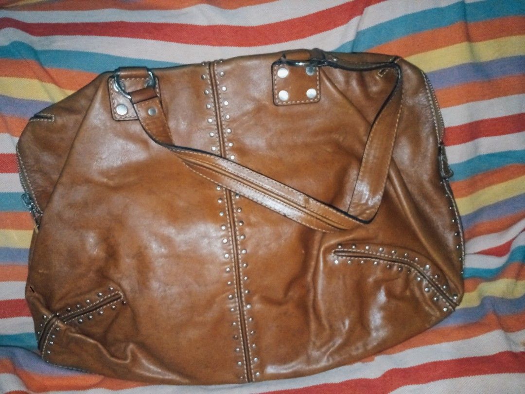 Michael Kors Brown Leather Studded Shoulder Bag (Category: Luxury Bags & Wallets) located in Manila. Submitted by littlelove25 (Listing ID 1471096652, Image 1). Description: - Brand: Michael Kors - Color: Tan Brown - Material: Genuine Leather with Silver Hardware Studs - Closure: Secure Zip Top - Interior: MK Monogram Lining with Multiple Slip Pockets & 1 Zip Pocket - Origin: Made in China Tag Intact - Condition: Excellent everyday bag with plent