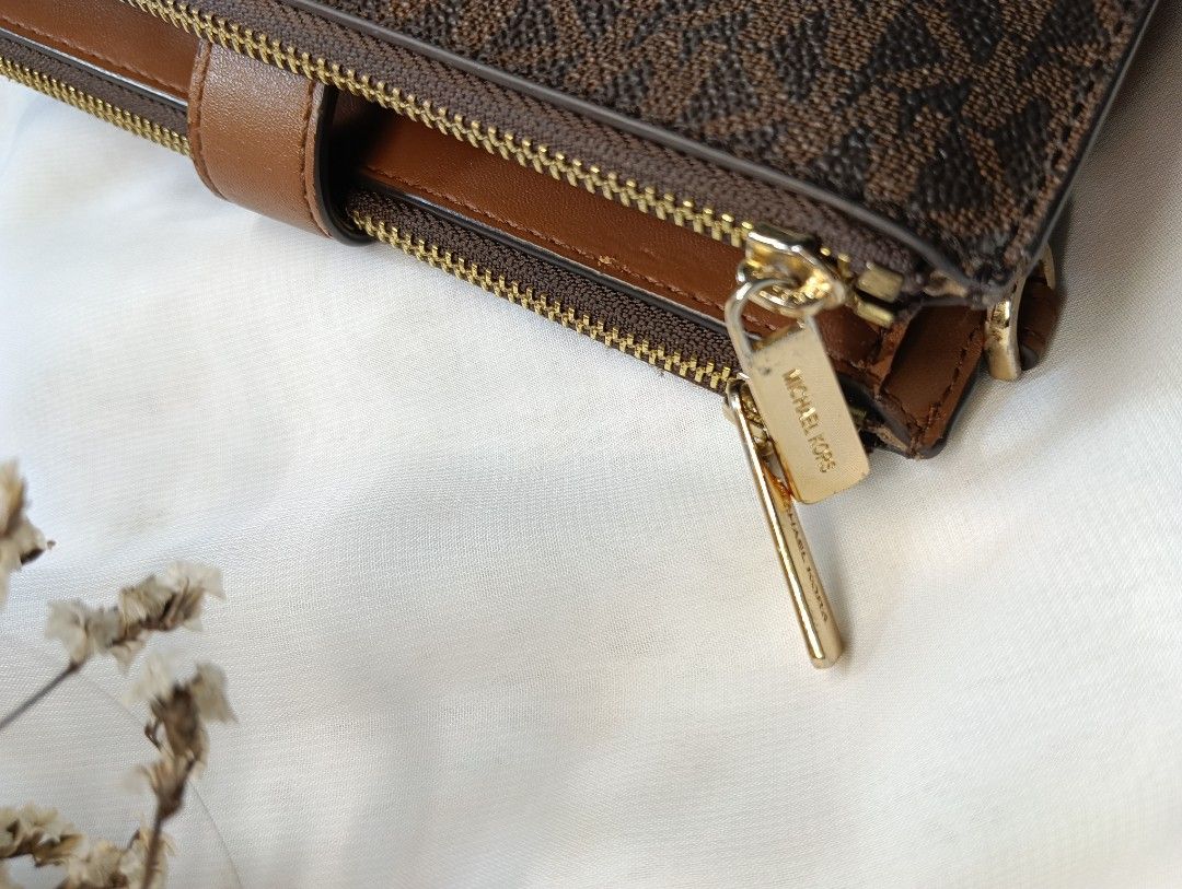 Michael Kors Brown Monogram Bi-Fold Zip Wallet (Category: Luxury Bags & Wallets) located in Quezon City. Submitted by sortedstyle (Listing ID 1470932558, Image 3). Description: - Brown monogram coated canvas with smooth tan leather trim - Gold-tone hardware with working zip pulls and snap closure - Interior includes multiple card slots, cash compartment, and zipped pouch - Condition note: Shows cracking and wear along the edges - 100% functional 