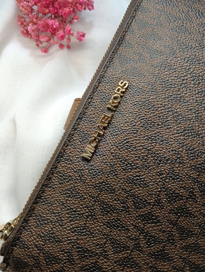 Michael Kors Brown Monogram Bi-Fold Zip Wallet (Category: Luxury Bags & Wallets) located in Quezon City. Submitted by sortedstyle (Listing ID 1470932558, Image 2). Description: - Brown monogram coated canvas with smooth tan leather trim - Gold-tone hardware with working zip pulls and snap closure - Interior includes multiple card slots, cash compartment, and zipped pouch - Condition note: Shows cracking and wear along the edges - 100% functional 