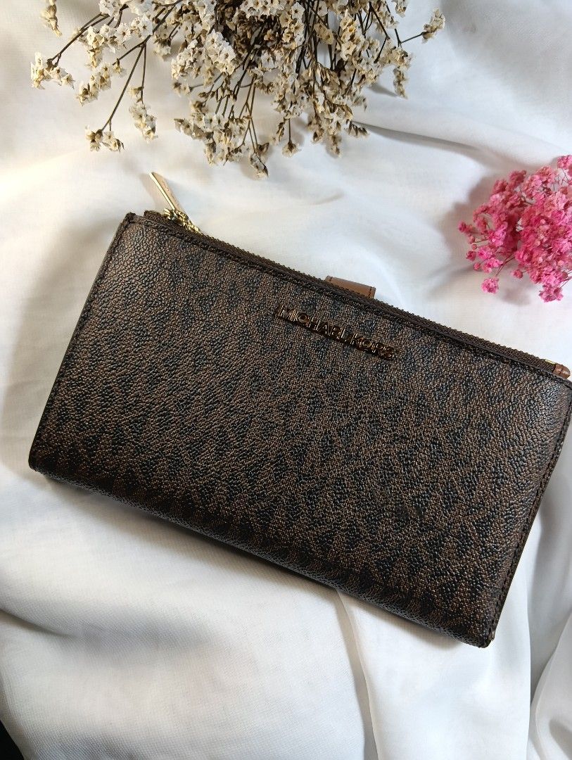 Michael Kors Brown Monogram Bi-Fold Zip Wallet (Category: Luxury Bags & Wallets) located in Quezon City. Submitted by sortedstyle (Listing ID 1470932558, Image 1). Description: - Brown monogram coated canvas with smooth tan leather trim - Gold-tone hardware with working zip pulls and snap closure - Interior includes multiple card slots, cash compartment, and zipped pouch - Condition note: Shows cracking and wear along the edges - 100% functional 