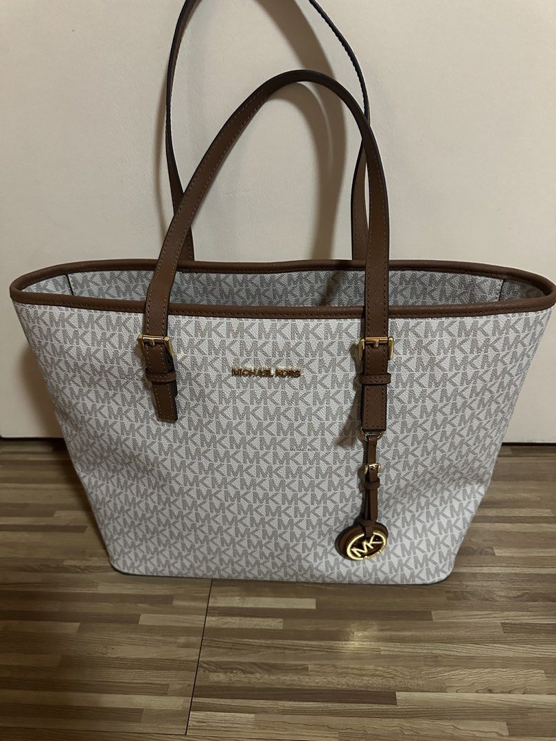 Michael Kors MK Monogram Tote Bag Brown White (Category: Tote Bags) located in San Juan City. Submitted by luluhonolulu (Listing ID 1471081587, Image 1). Description: - Authentic Michael Kors tote bag in classic white/grey monogram - Elegant brown leather handles, trim, and gold-tone hardware - Includes signature hanging MK logo charm - Secure zip-top closure - Spacious interior featuring open slip pockets and a key leash strap - Structured, self