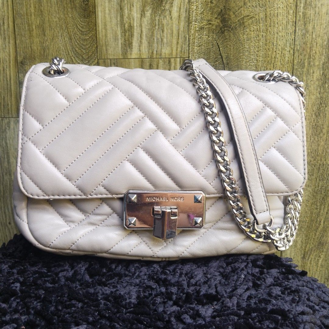 Michael Kors Quilted Shoulder Bag Grey Silver Chain (Category: Luxury Bags & Wallets) located in Lubao. Submitted by dione_closet503 (Listing ID 1470933609, Image 1). Description: - Color: Light Grey - Material: Quilted leather with chevron pattern - Hardware: Silver-toned with stylish stud accents - Closure: Secure turn-lock closure - Strap: Convertible chain strap for shoulder or crossbody wear - Size: Ideal everyday size that easily fits your 