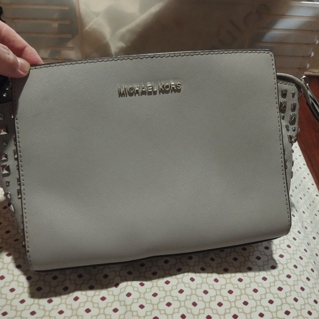 Michael Kors Studded Crossbody Bag Light Grey (Category: Cross-body Bags) located in Manila. Submitted by lene48 (Listing ID 1471050625, Image 2). Description: - Brand: Michael Kors - Material: Premium Saffiano leather - Color: Light grey with silver-tone hardware - Design: Chic metal pyramid studs on both side gussets - Closure: Secure zip top closure - Interior: Fabric lining with convenient slip pockets - Strap: Attached and adjustable for a c