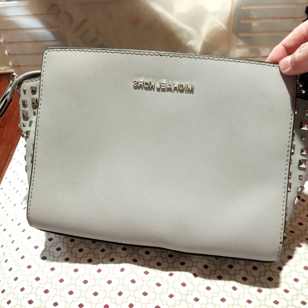 Michael Kors Studded Crossbody Bag Light Grey (Category: Cross-body Bags) located in Manila. Submitted by lene48 (Listing ID 1471050625, Image 1). Description: - Brand: Michael Kors - Material: Premium Saffiano leather - Color: Light grey with silver-tone hardware - Design: Chic metal pyramid studs on both side gussets - Closure: Secure zip top closure - Interior: Fabric lining with convenient slip pockets - Strap: Attached and adjustable for a c