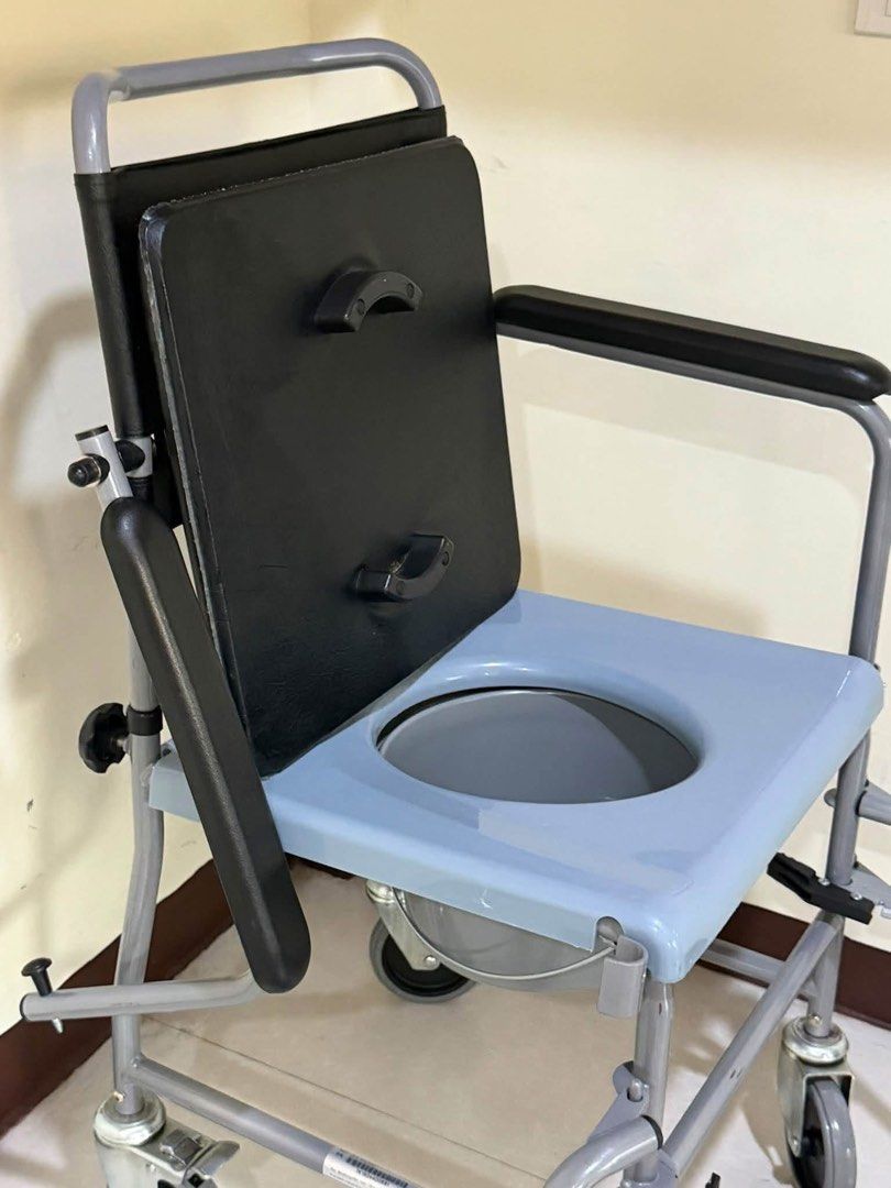 Mobile Commode Wheelchair with Detachable Bucket (Category: Wheelchairs) located in Manila. Submitted by calmdolphin.87b0e4 (Listing ID 1470955394, Image 2). Description: - Durable grey steel frame designed for elderly care and home mobility - Comfortable padded black backrest and seat cushion - Convenient removable commode bucket with lid and blue plastic toilet seat - Four locking caster wheels for safety and easy movement - Foldable footrests 