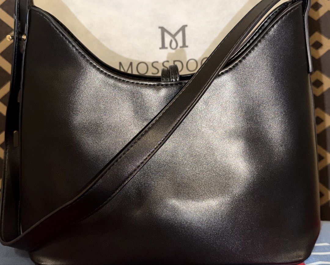Mossdoom Black Shoulder Bag (Category: Shoulder Bags) located in Manila. Submitted by nayeoniescart (Listing ID 1471094320, Image 2). Description: PRE LOVED: Mossdoom black shoulder bag (bought @ sh.0pee) - Condition: Good and pristine (used only for a few times) - Gold-tone hardware accents, dual decorative front straps with rings. Minimalist branding stamped near the bottom. Adjustable long shoulder strap attached at sides. Clean interior linin