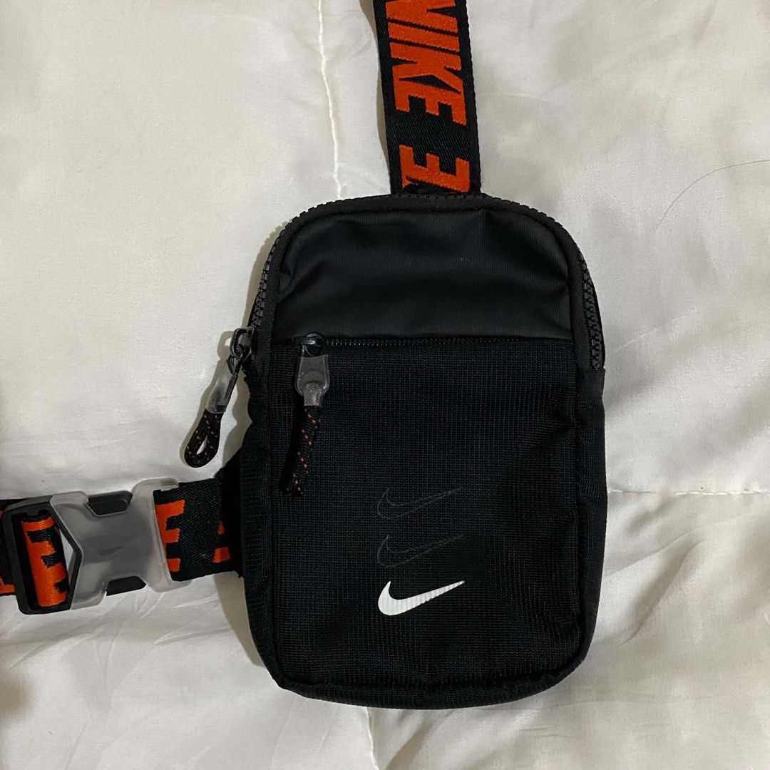 Nike Essentials Cross body bag (Category: Sling Bags) located in Manila. Submitted by jiiiiiiiiiims (Listing ID 1471046344, Image 2). Description: - Authentic Nike crossbody bag in versatile black - Eye-catching orange strap lettering and classic white Nike swoosh logo - Durable nylon and polyester construction built to last - Multiple zippered compartments to keep your daily essentials organized - Adjustable buckle strap for a secure and customi