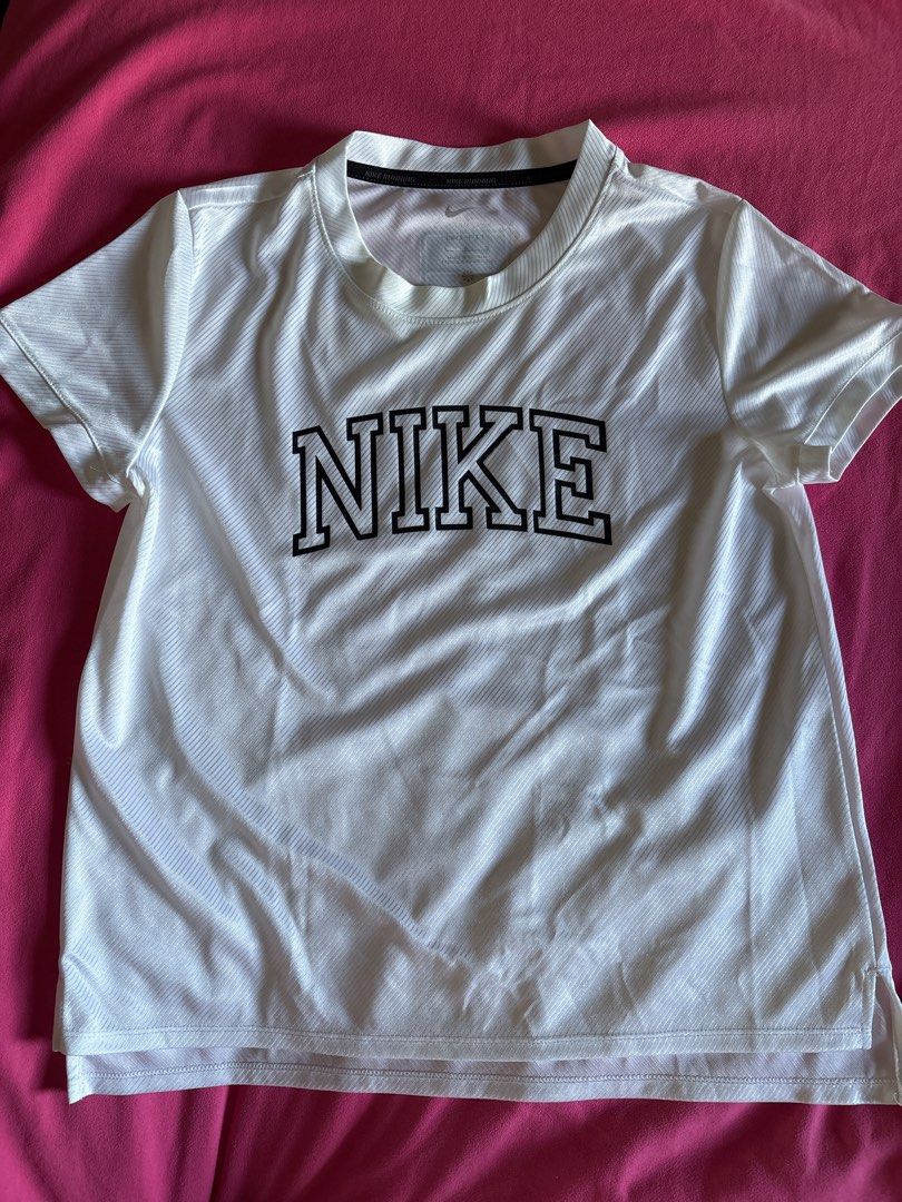 Nike Running Dri-FIT White T-Shirt (Category: Activewear) located in Cainta. Submitted by PreLovedbyANM (Listing ID 1471010831, Image 1). Description: - Authentic Nike running t-shirt in crisp white - Size M with printed inner collar tag - Features a bold, large black collegiate NIKE graphic on the front - Dri-FIT moisture-wicking technology with a diagonal ribbed texture - Black Nike Team tag near the back collar and branded running taping insid