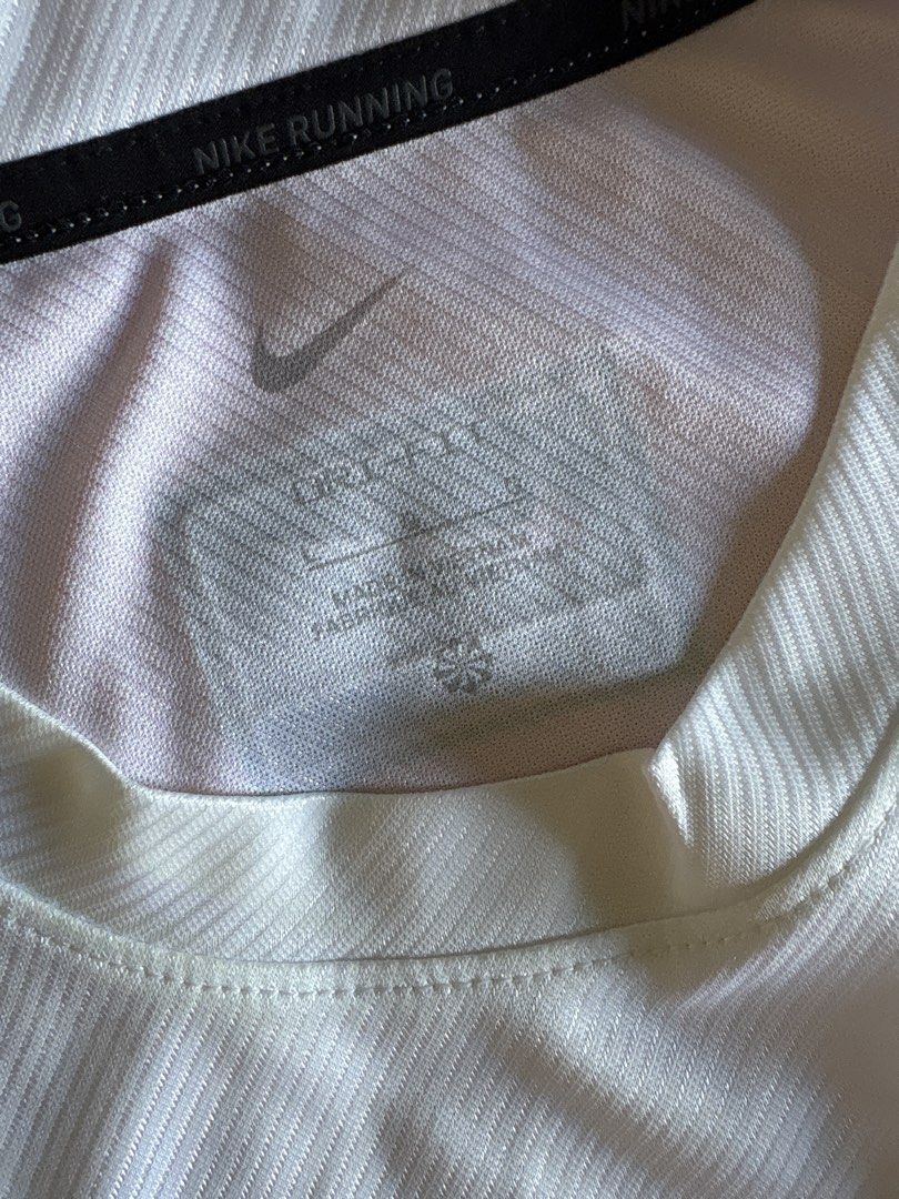Nike Running Dri-FIT White T-Shirt (Category: Activewear) located in Cainta. Submitted by PreLovedbyANM (Listing ID 1471010831, Image 2). Description: - Authentic Nike running t-shirt in crisp white - Size M with printed inner collar tag - Features a bold, large black collegiate NIKE graphic on the front - Dri-FIT moisture-wicking technology with a diagonal ribbed texture - Black Nike Team tag near the back collar and branded running taping insid