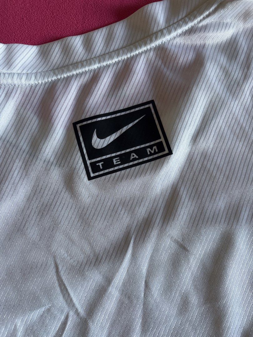 Nike Running Dri-FIT White T-Shirt (Category: Activewear) located in Cainta. Submitted by PreLovedbyANM (Listing ID 1471010831, Image 3). Description: - Authentic Nike running t-shirt in crisp white - Size M with printed inner collar tag - Features a bold, large black collegiate NIKE graphic on the front - Dri-FIT moisture-wicking technology with a diagonal ribbed texture - Black Nike Team tag near the back collar and branded running taping insid