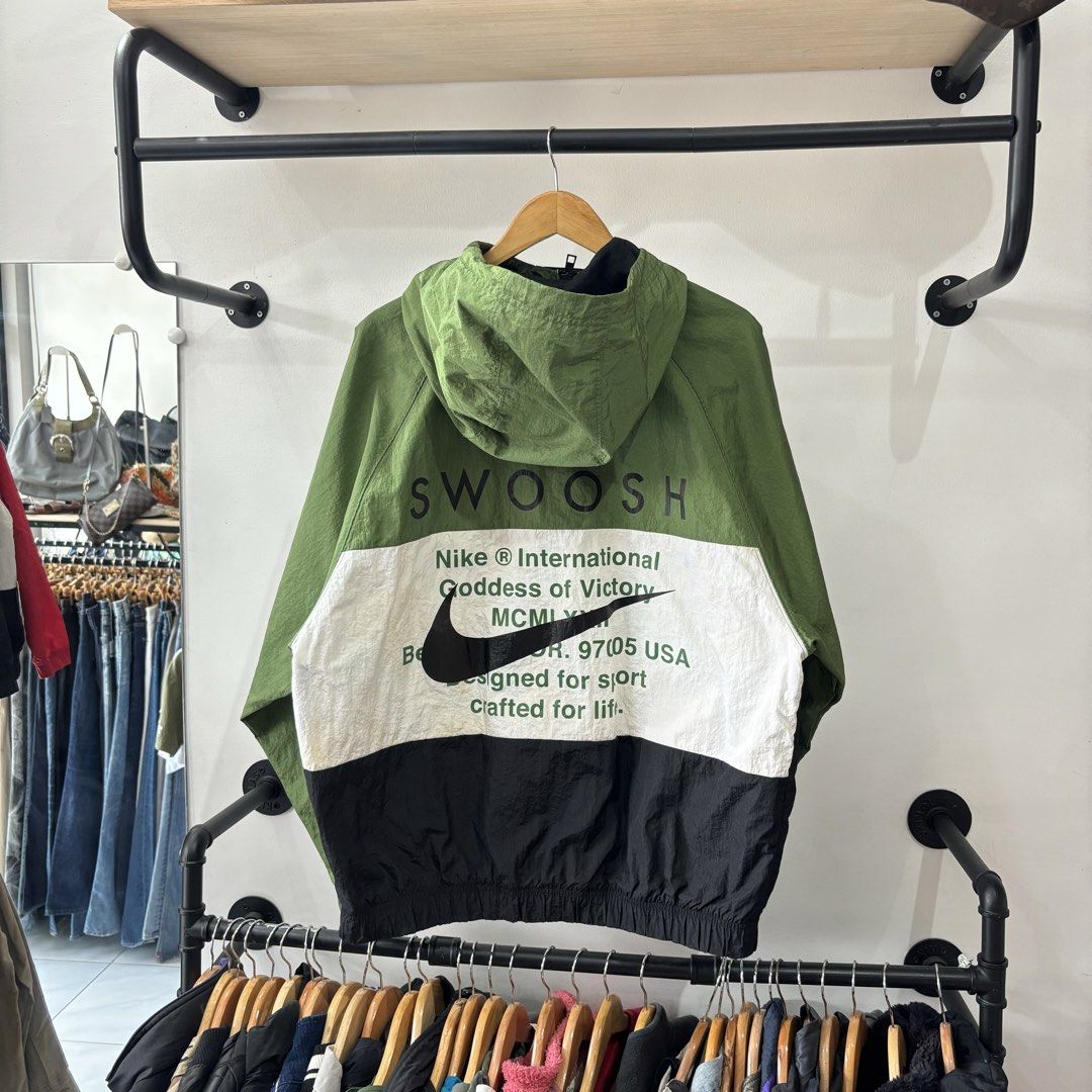 Nike Swoosh Colorblock Windbreaker Jacket (Category: Coats, Jackets and Outerwear) located in Bambang. Submitted by heats777 (Listing ID 1471039450, Image 3). Description: - Brand: Nike - Style: Colorblock windbreaker (Green/White/Black) - Logos: Double Swoosh on chest, large Swoosh text on back - Material: Lightweight nylon shell with breathable mesh lining - Features: Drawstring hood and front pockets - Size: XXL (Made in China) - Issue: Last 2