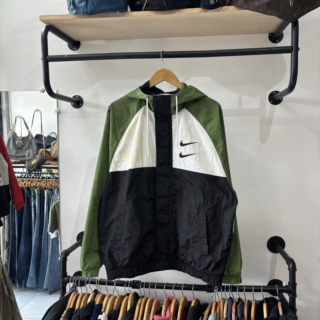 Nike Swoosh Colorblock Windbreaker Jacket (Category: Coats, Jackets and Outerwear) located in Bambang. Submitted by heats777 (Listing ID 1471039450, Image 2). Description: - Brand: Nike - Style: Colorblock windbreaker (Green/White/Black) - Logos: Double Swoosh on chest, large Swoosh text on back - Material: Lightweight nylon shell with breathable mesh lining - Features: Drawstring hood and front pockets - Size: XXL (Made in China) - Issue: Last 2