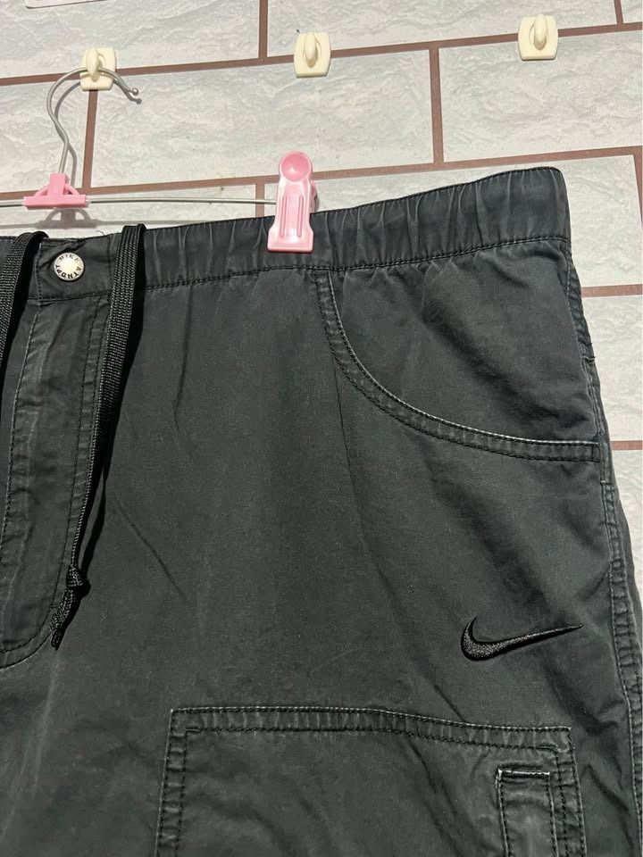 Nike The Athletic Dept. Cargo Shorts (Category: Shorts) located in Cagayan de Oro. Submitted by thrift4all (Listing ID 1471003476, Image 2). Description: - Brand: Nike (The Athletic Dept.) - Size: XL - Color: Black - Material & Fit: Elastic waistband with adjustable drawstring closure - Storage: Multiple functional cargo pockets on the sides - Details: Embroidered Nike swoosh near the left pocket and button detail on the front cargo flap - Condit