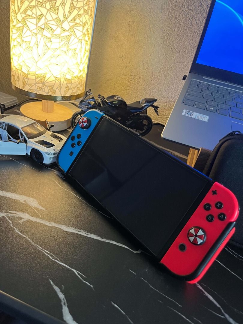 Nintendo Switch OLED Neon Blue and Red Console (Category: Nintendo) located in Caloocan City. Submitted by grandmountain.58b9fc (Listing ID 1471046664, Image 2). Description: Nintendo Switch handheld console with Neon Blue/Red Joy-Cons, custom umbrella thumb grips, black protective case, and screen protector. Fully functional for both portable and docked play. Ready to use! Note: Unit and charger only!!.