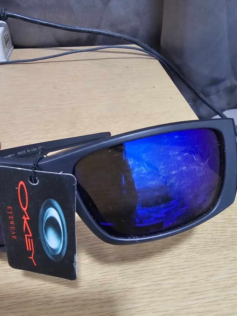 Oakley Eyewear Sunglasses Blue Lenses (Category: Sunglasses & Eyewear) located in Caloocan City. Submitted by smart_shoppers_ville (Listing ID 1470953817, Image 2). Description: - Brand: Oakley - Origin: Made in USA - Frame: Matte black with unique retro style and distinctive sculpted temples featuring blue accents - Lenses: Bold blue mirrored (Please note: shows minor scuffs and surface scratches) - Details: Temple text reads 'Made in USA' and '