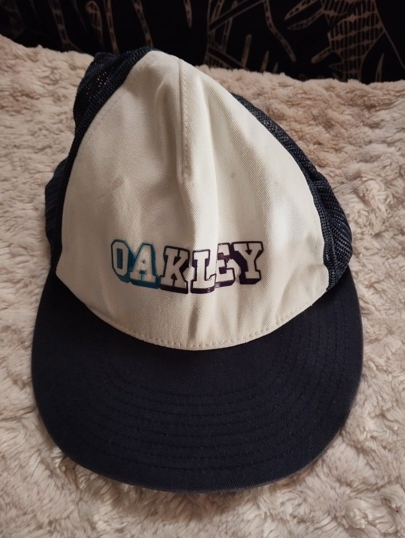 Oakley Trucker Cap Snapback (Category: Caps & Hats) located in Manila. Submitted by cosmictree_1321 (Listing ID 1471009353, Image 1). Description: - Authentic Oakley trucker cap - Classic white front panel with bold gradient embroidered logo - Breathable dark mesh back for comfort - Adjustable plastic snapback closure for a custom fit - Features structured brim and original interior sweatband with brand tags.
