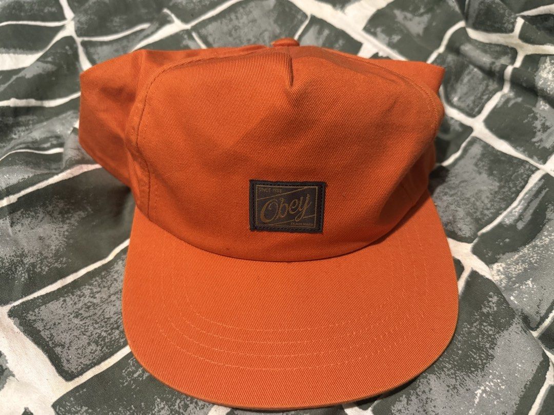 Obey orange snapback cap (Category: Caps & Hats) located in Manila. Submitted by safeowl.b6dbb0 (Listing ID 1471023861, Image 1). Description: - Brand: Obey - Style: Snapback cap with flat brim and structured crown - Color: Bright orange with front logo patch - Material: 100% cotton (Made in Bangladesh) - Features: Interior mesh front panel and adjustable snap closure - Size: One size fits all - Condition: Brand new.