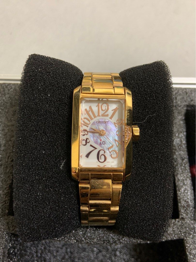 Orient Gold Rectangular Dial Women's Watch (Category: Women's Watches) located in Manila. Submitted by relokado (Listing ID 1470938288, Image 1). Description: - Brand: Orient - Design: Gold-tone rectangular case with a unique top-positioned crown - Dial: Mother-of-pearl background featuring large, stylized rose gold Arabic numerals - Strap: Matching gold metal link bracelet with minor everyday wear - Condition: Keeps time very well - Inclusion: C