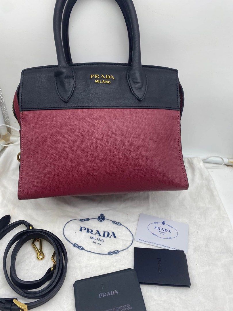 Orig Prada Esplanade Leather Handbag Red Black (Category: Luxury Bags & Wallets) located in Bacolod City. Submitted by chuchaystuffs (Listing ID 1470944904, Image 2). Description: - Authentic Prada Esplanade Handbag - Material: Premium Saffiano leather in contrasting red and black - Hardware: Gold-tone with iconic Prada Milano lettering - Design: Structured trapezoid silhouette with top zip closure - Versatility: Dual top handles and a detachable
