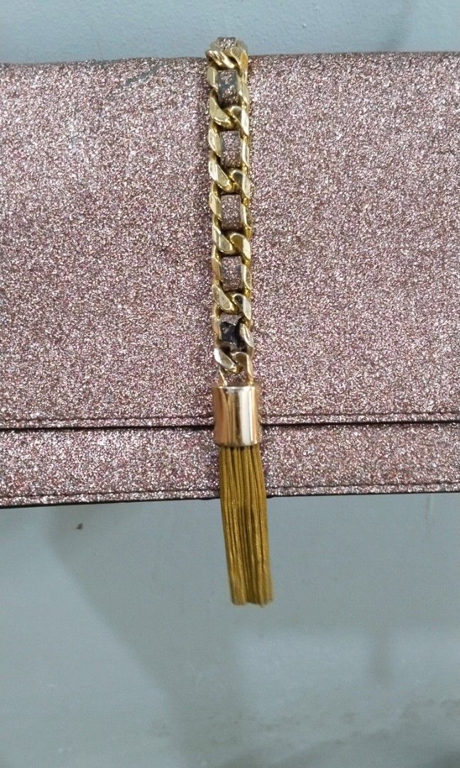 Party chain sling bag (Category: Cross-body Bags) located in Trece Martires City. Submitted by vherma (Listing ID 1470947910, Image 2). Description: rose-gold or pink glitter-finish evening clutch or sling bag with a gold-tone chain strap and a vertical gold center accent with a tassel drop..