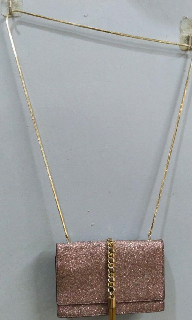 Party chain sling bag (Category: Cross-body Bags) located in Trece Martires City. Submitted by vherma (Listing ID 1470947910, Image 1). Description: rose-gold or pink glitter-finish evening clutch or sling bag with a gold-tone chain strap and a vertical gold center accent with a tassel drop..