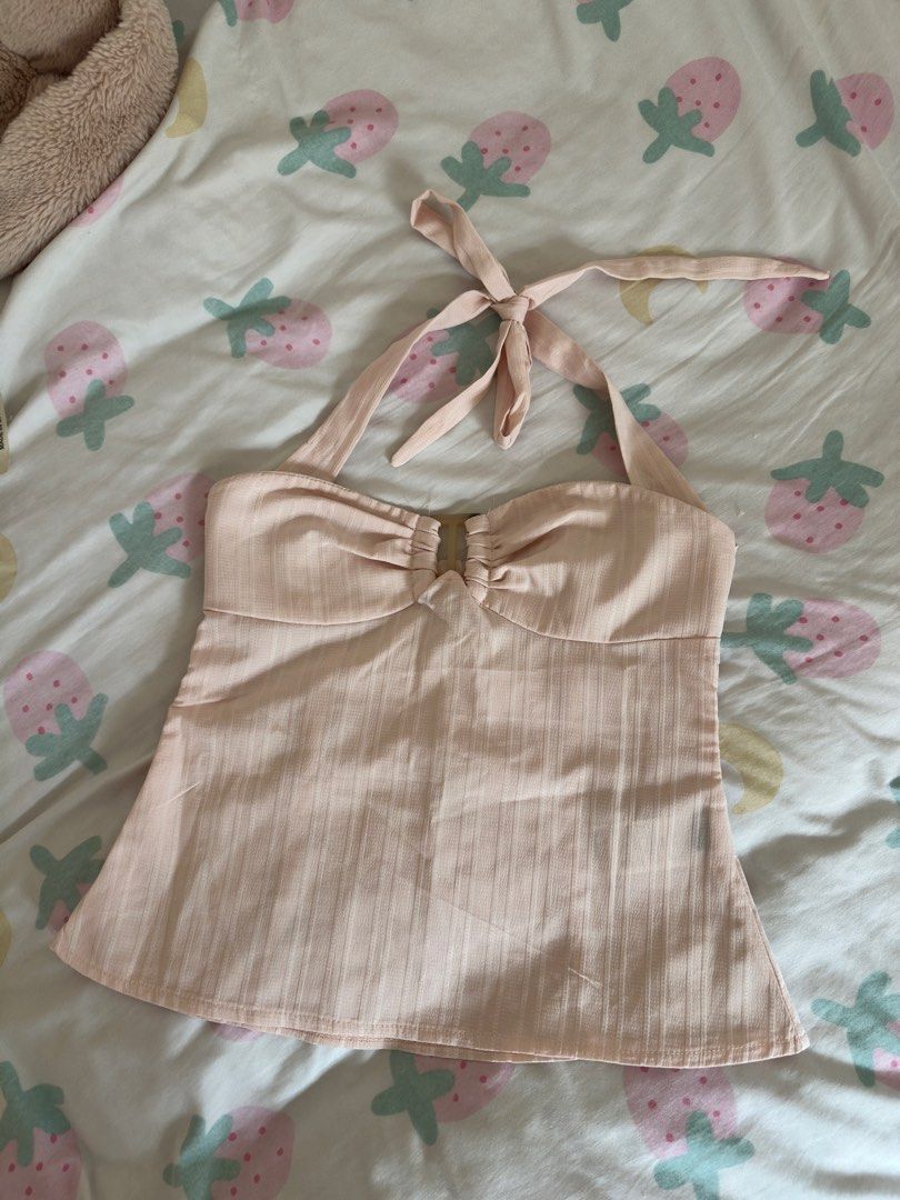 Pastel Pink Halter Top with Front Ring Detail (Category: Sleeveless) located in Manila. Submitted by preloved-bycath (Listing ID 1471078874, Image 1). Description: - Color: Light pink - Design: Halter neck with self-tie straps and a cute central ring detail on the bust - Fabric: Textured with subtle vertical stripes - Fit: Gathered cups and an A-line flared hem - Style: Great for warm weather, beach days, or layering - Condition: Brand new / Exce