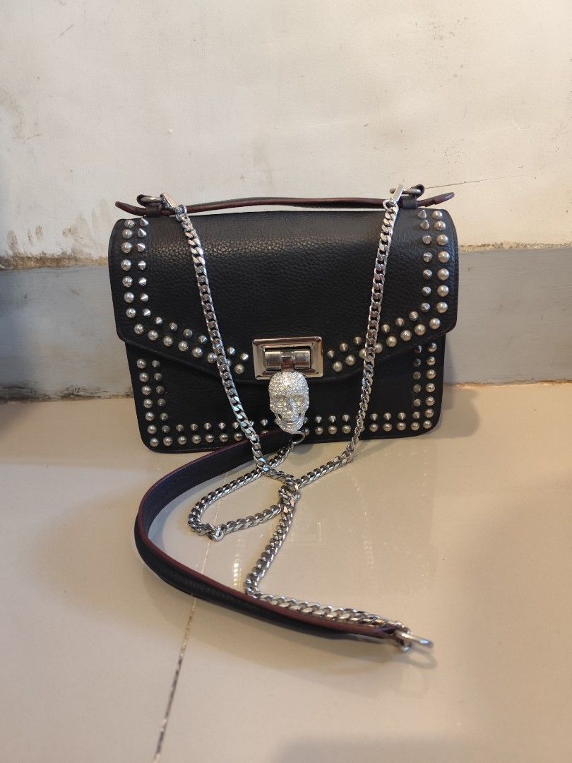 Philipp Plein Black Studded Skull Handbag (Category: Luxury Bags & Wallets) located in Caloocan City. Submitted by zenkithriftsph (Listing ID 1470960158, Image 1). Description: - Authentic black calf leather handbag with striking metal stud detailing - Dual carrying options: silver-tone chain strap and sturdy top handle - Eye-catching rhinestone skull lock closure on the front flap - Interior features durable black polyester patterned lining and 