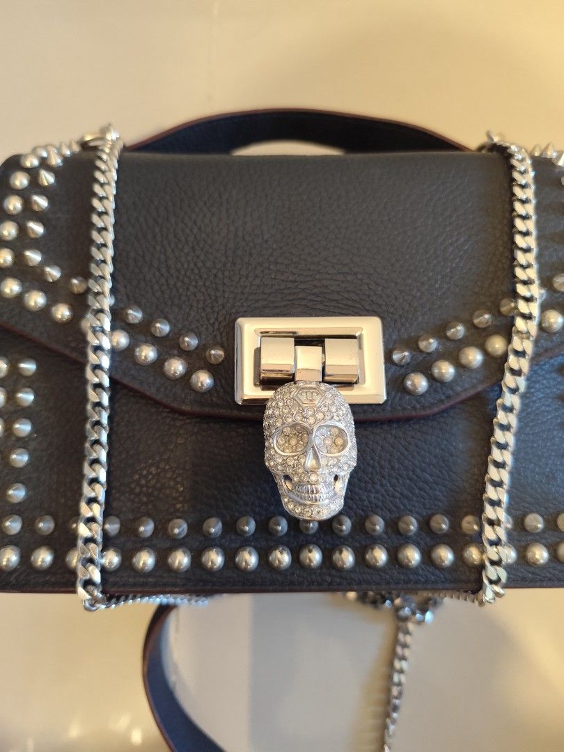 Philipp Plein Black Studded Skull Handbag (Category: Luxury Bags & Wallets) located in Caloocan City. Submitted by zenkithriftsph (Listing ID 1470960158, Image 2). Description: - Authentic black calf leather handbag with striking metal stud detailing - Dual carrying options: silver-tone chain strap and sturdy top handle - Eye-catching rhinestone skull lock closure on the front flap - Interior features durable black polyester patterned lining and 