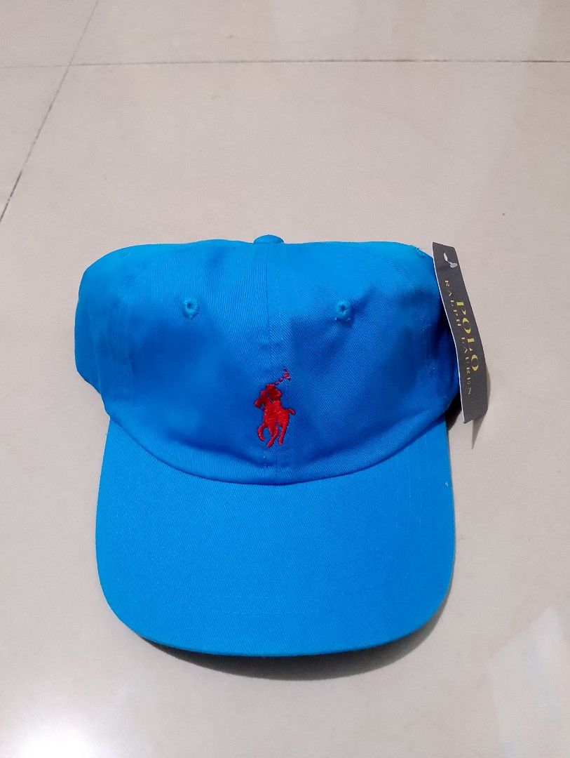 Polo Ralph Lauren Blue Baseball Cap Hat (Category: Caps & Hats) located in Manila. Submitted by thriftyboyzzz (Listing ID 1470998394, Image 1). Description: - Brand: Polo Ralph Lauren - Color: Bright blue with red accents - Design: Embroidered red pony logo on front, red POLO text on back - Material: 100% cotton - Fit: Adjustable metal buckle strap with engraved POLO branding - Condition: Brand new with original tags attached - Origin: Made in Ba