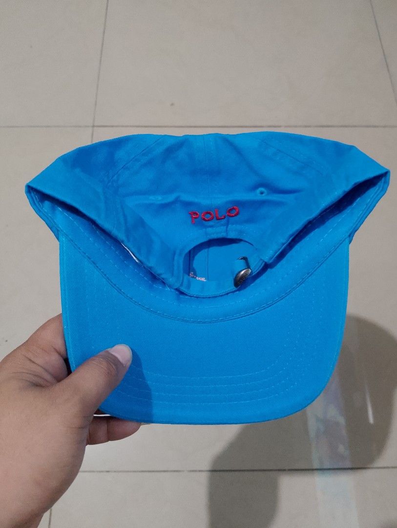 Polo Ralph Lauren Blue Baseball Cap Hat (Category: Caps & Hats) located in Manila. Submitted by thriftyboyzzz (Listing ID 1470998394, Image 2). Description: - Brand: Polo Ralph Lauren - Color: Bright blue with red accents - Design: Embroidered red pony logo on front, red POLO text on back - Material: 100% cotton - Fit: Adjustable metal buckle strap with engraved POLO branding - Condition: Brand new with original tags attached - Origin: Made in Ba